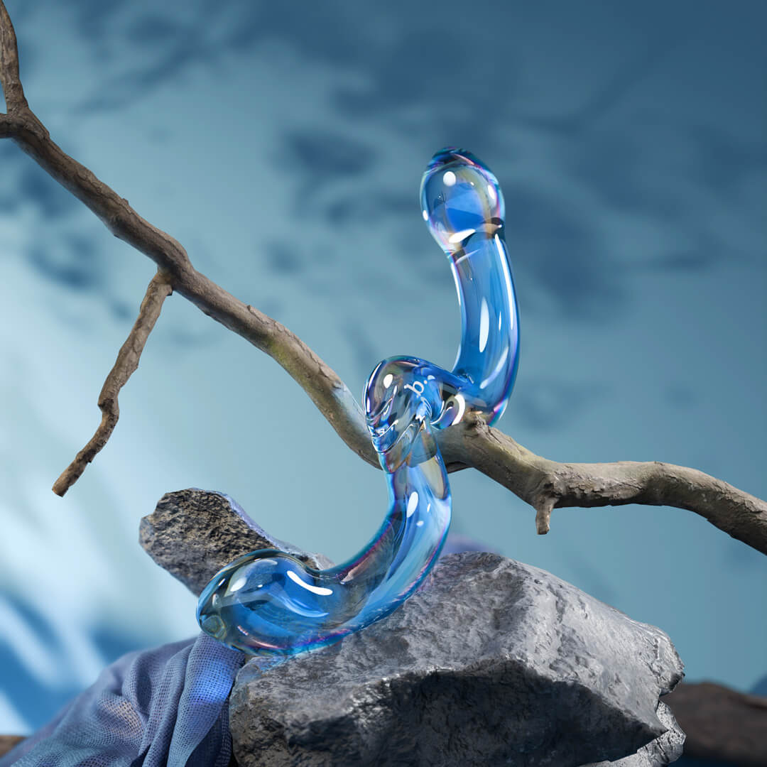 Biird's blue glass object resting on a bare branch against a blue backdrop